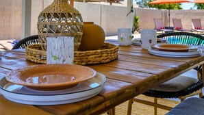 An outdoor patio with a wooden table set for dining, featuring woven baskets, plates, and a decorative vase. - Stylish Phoenix home | Private pool | Spacious living | Family & sports-friendly | Close to Phoenix Zoo, Desert Botanical Garden, ASU, and State Farm Stadium (Phoenix)