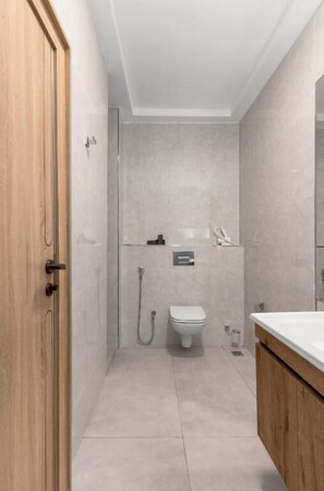 A modern bathroom with a shower, toilet, and sink. - STP Apartments (Abuja)