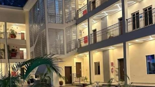 A multi-level hotel atrium with balconies, potted plants, and a tiled floor. - STP Apartments (Abuja)