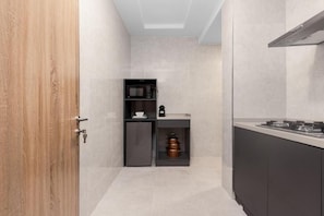 A compact kitchen with a microwave, a small refrigerator, and a gas stove. - STP Apartments (Abuja)