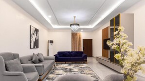 A modern living room with a grey sofa, a blue sofa, and a marble coffee table. - STP Apartments (Abuja)