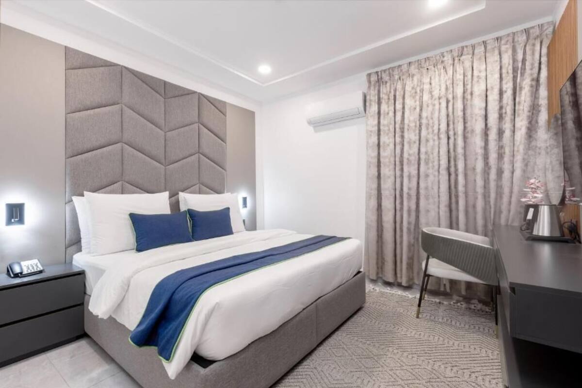 A modern hotel room with a large bed, bedside tables, a desk, and a chair.