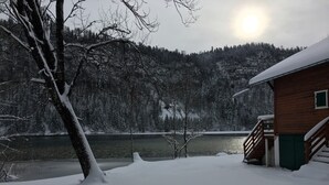 Une cabane au bord d’un lac, entourée d’un paysage enneigé.