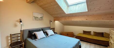 Ein Schlafzimmer mit Oberlicht, einem Bett, einer Bank und einer Kommode.