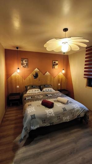 Ein Schlafzimmer mit einem hölzernen Kopfende, einem Bett mit gemusterten Betttextilien, zwei Nachttischlampen und einem Deckenventilator.