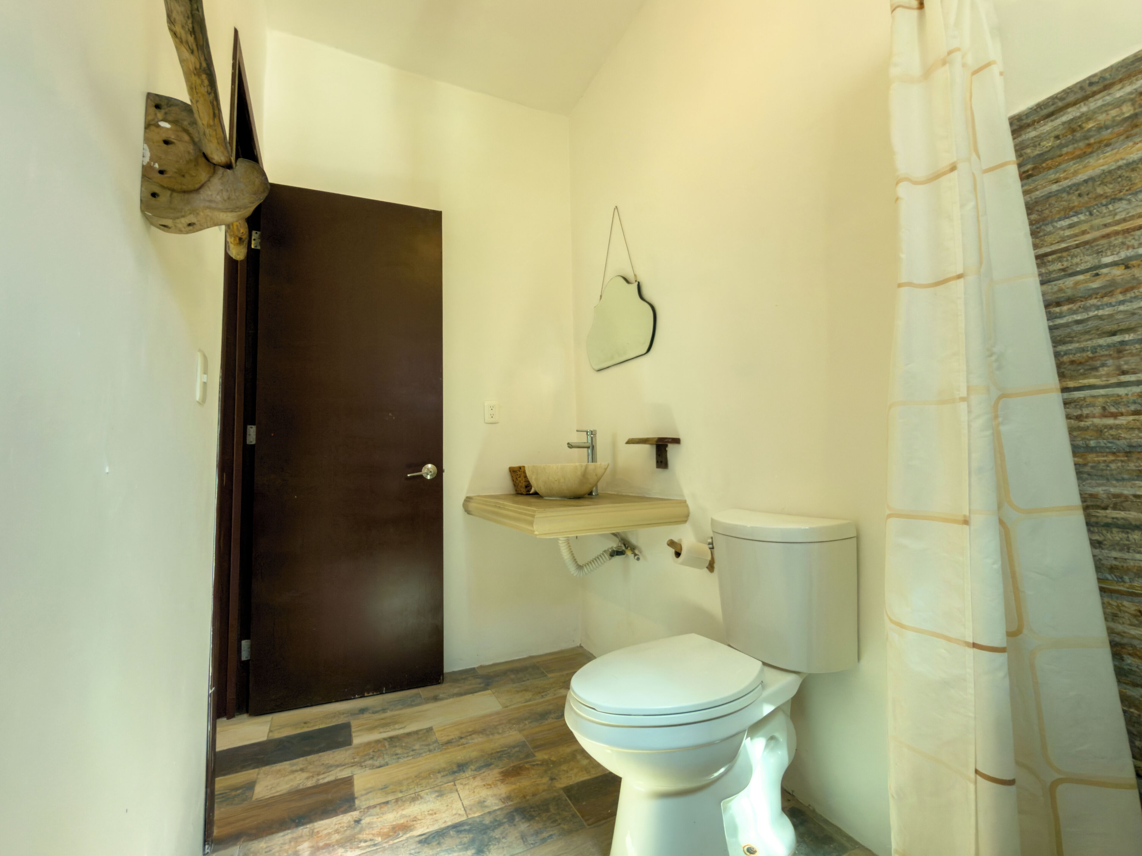 Een badkamer met een houten deur, een wastafel, een toilet en een douchegordijn.