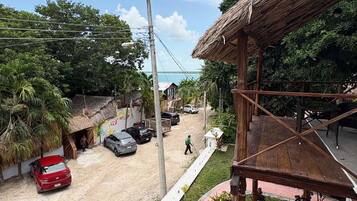 Vista de una calle con coches estacionados, un edificio con techo de paja y una estructura de madera con techo.