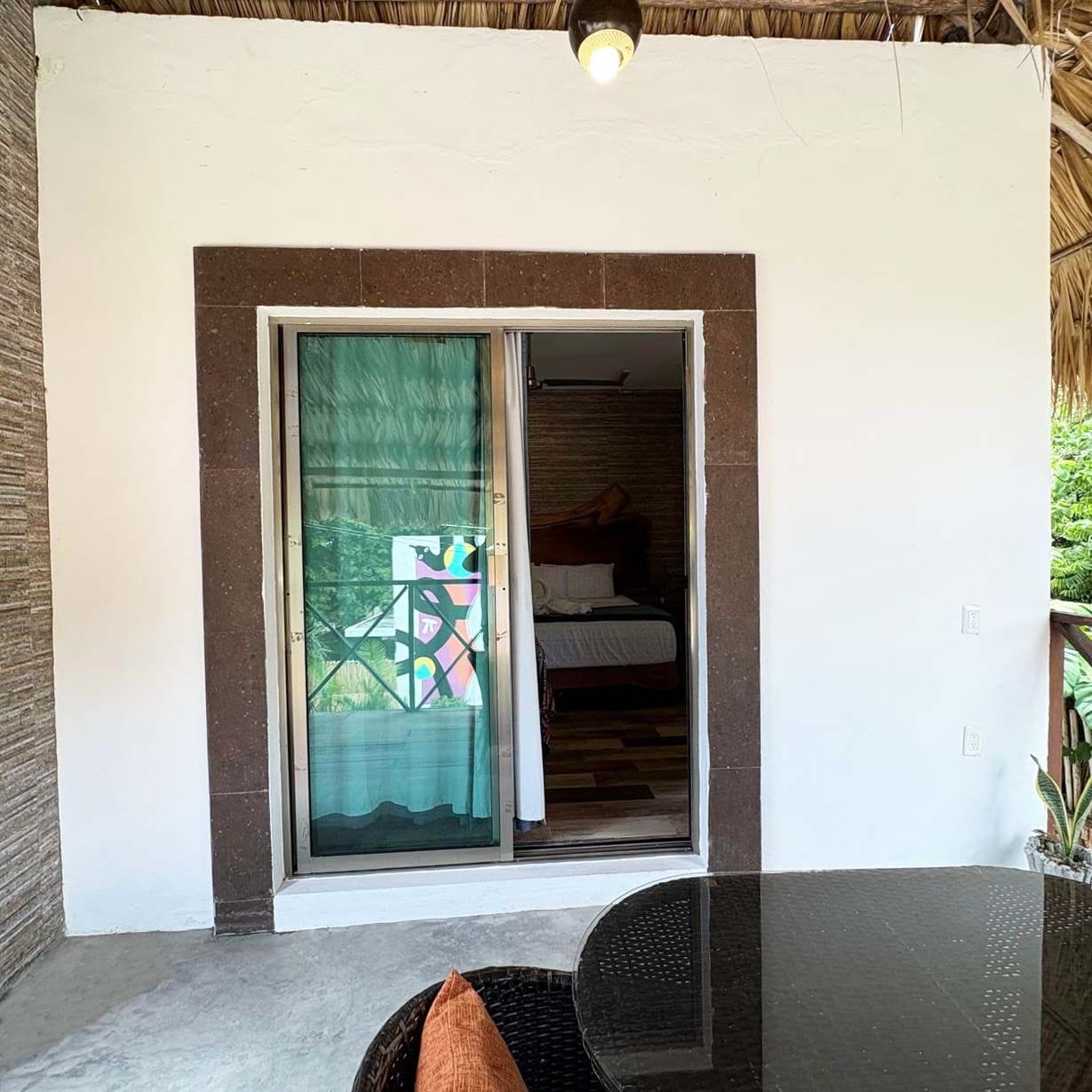A room with a bed, a window with a geometric pattern, and a sliding door.