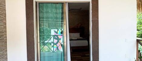 A room with a bed, a window with a geometric pattern, and a sliding door.