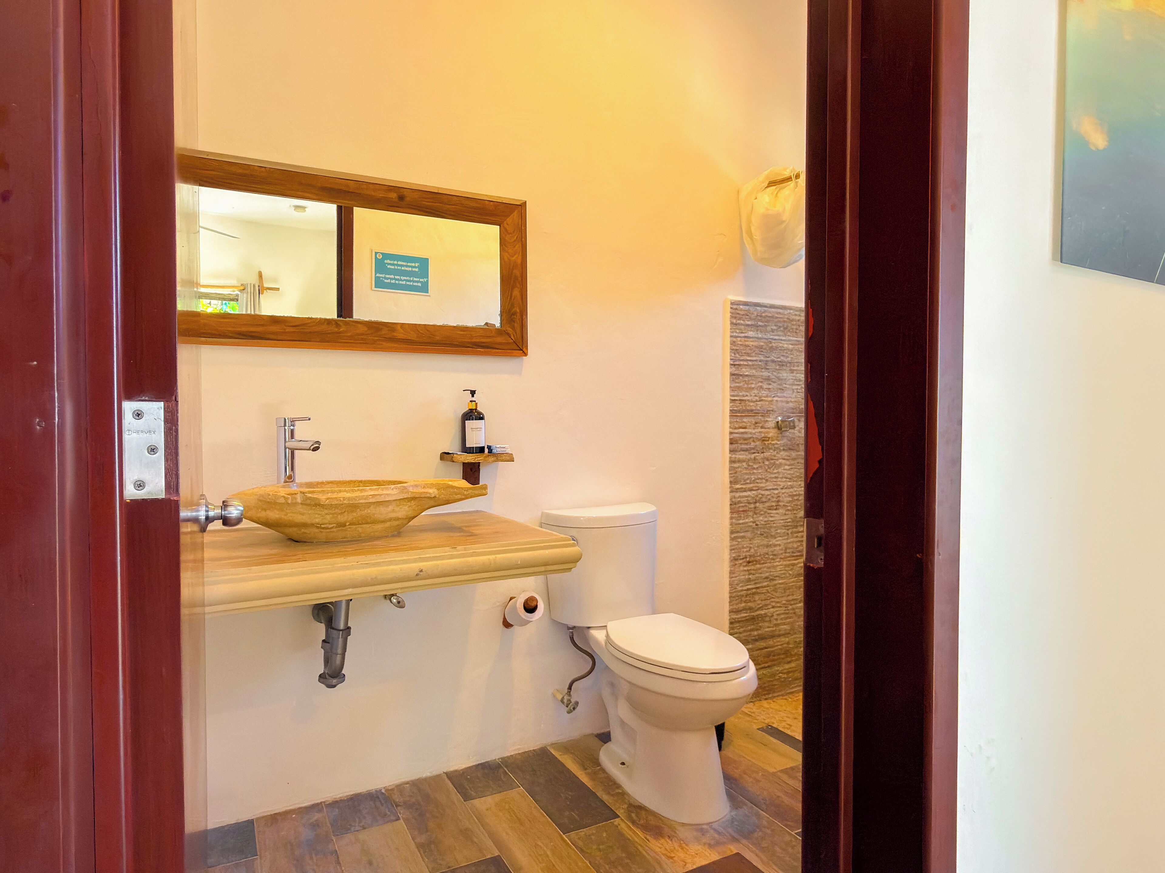 A bathroom with a wooden vanity, a sink, a toilet, and a mirror.