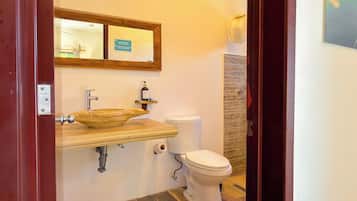 A bathroom with a wooden vanity, a sink, a toilet, and a mirror.