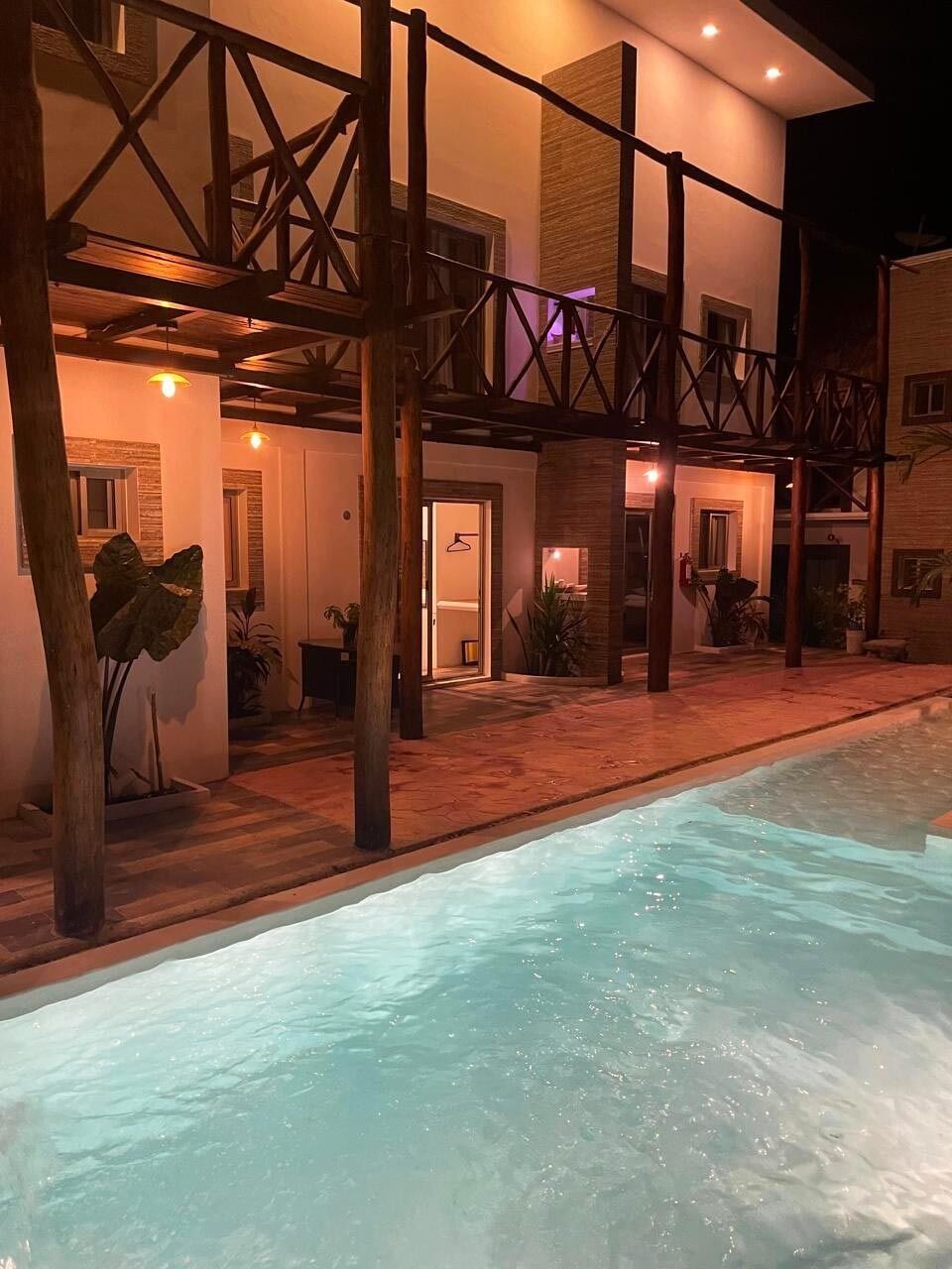 A poolside area with a wooden deck, a pool, and a building with a balcony.