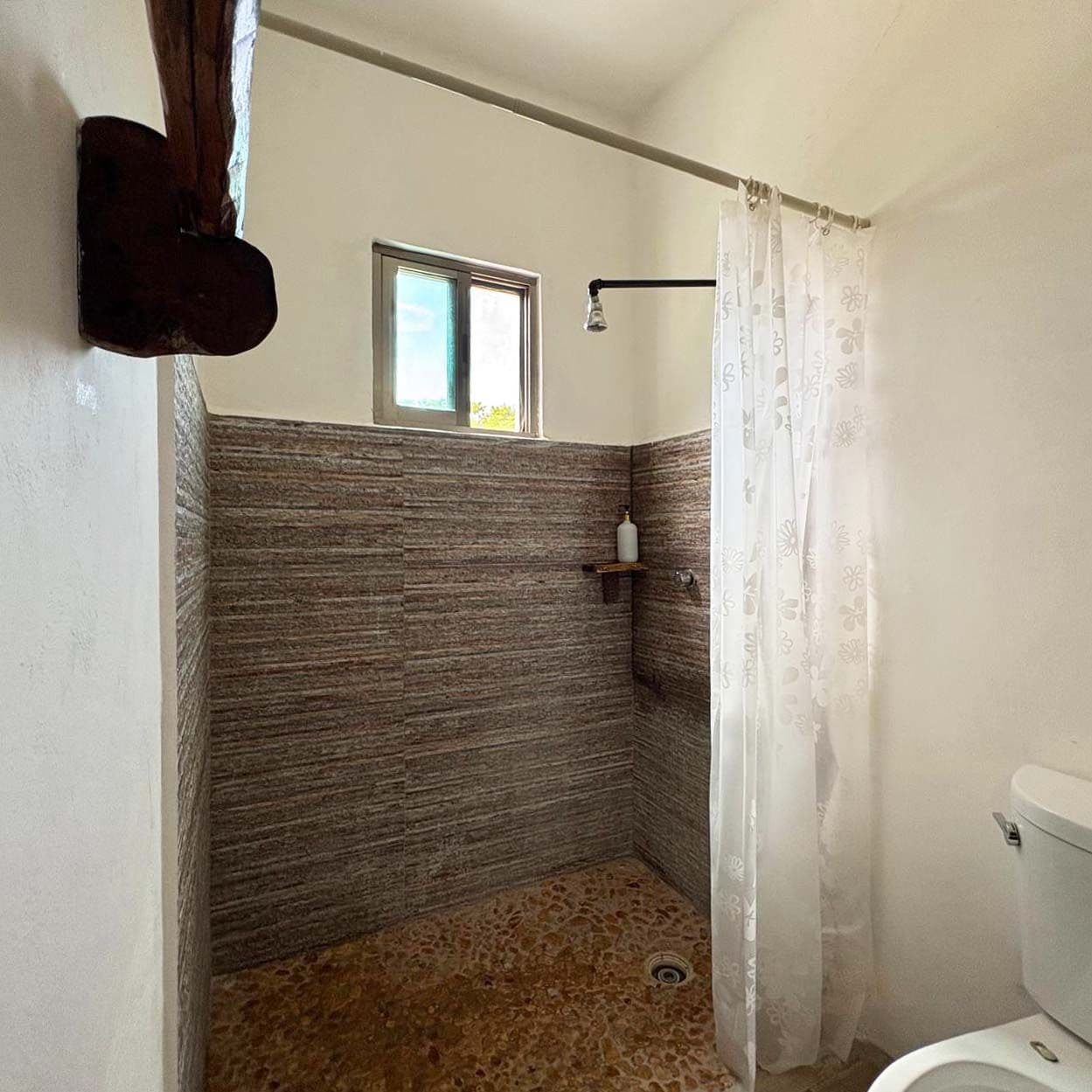 Ein Badezimmer mit Dusche, Fenster und Toilette.