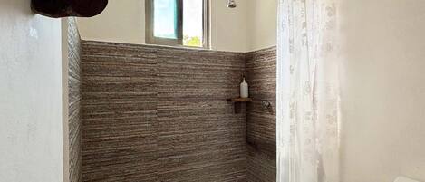 Ein Badezimmer mit Dusche, Fenster und Toilette.