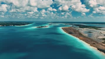An aerial view of a coastal area with clear blue waters, sandy beaches, and scattered islands.