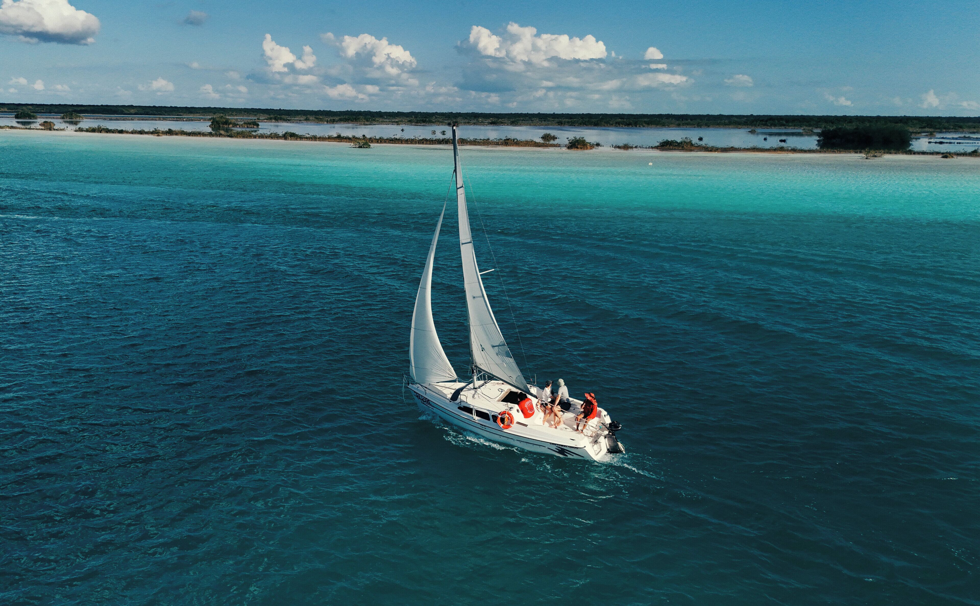 A sailboat on turquoise waters with a clear sky.