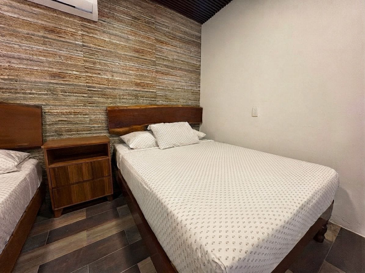 A bedroom with a wooden headboard bed, a nightstand, and a wall with a textured pattern.