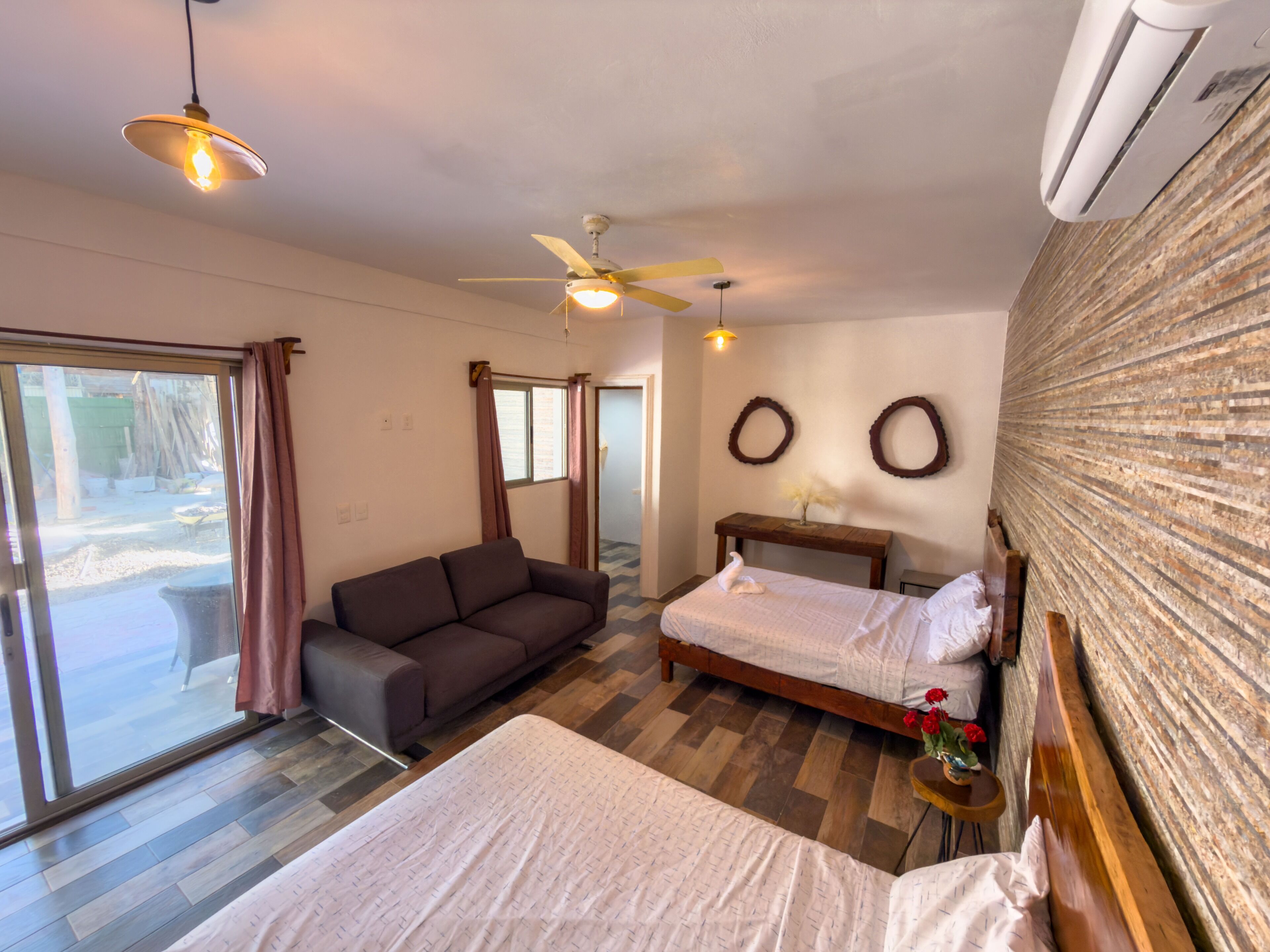 Un dormitorio con cama, sofá, ventilador de techo y ventana.