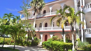 Un edificio de varios pisos con fachada blanca, techo de tejas rojas y balcones.