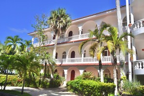 A multi-story building with a white facade, red-tiled roof, and balconies. - Oceanview Hideaway Apartment, Steps from the Beach (Cabarete)