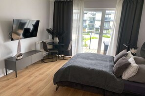 Ein modernes Schlafzimmer mit Bett, Schreibtisch, Stuhl, Fernseher und einem Balkon mit Blick.