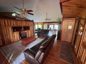 Ein rustikales Holzhaus-Interieur mit Kamin, Ledersofa, Essbereich und Holzwänden.