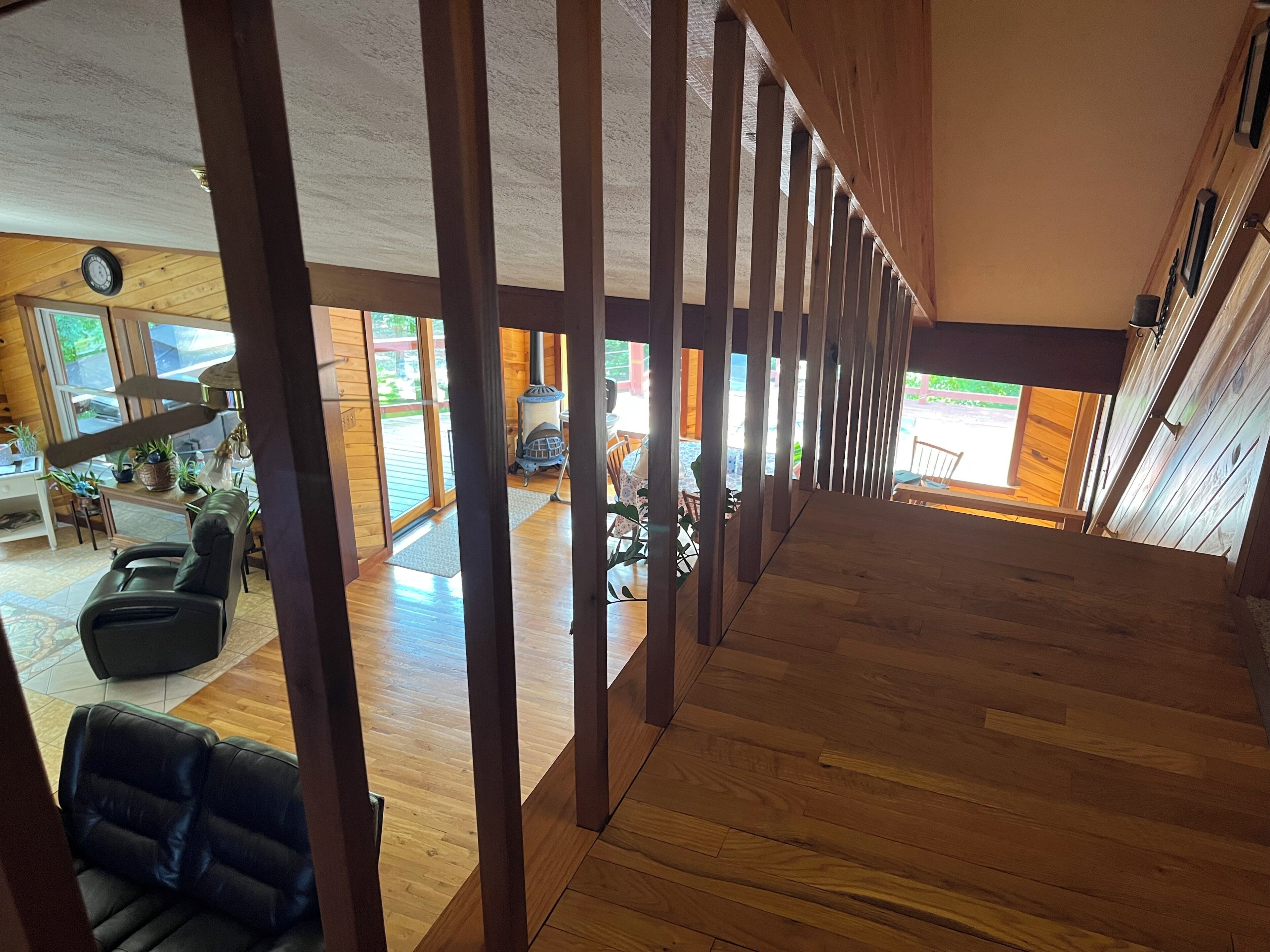 A spacious interior with a wooden floor, a seating area with a sofa, and a view of the outdoors through large windows.