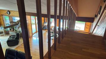 A spacious interior with a wooden floor, a seating area with a sofa, and a view of the outdoors through large windows.