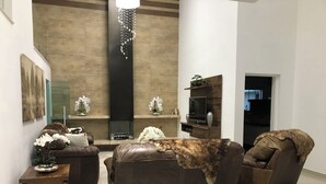 A modern living room with a brown leather sofa, a wooden coffee table, and a TV on a wooden stand. - Unique Alta Vista Pousada Boutique (Córrego do Bom Jesus)