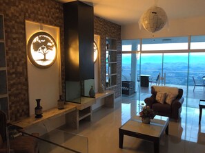 A modern living room with a large mirror, a fireplace, and a view of the mountains through large windows. - Unique Alta Vista Pousada Boutique (Córrego do Bom Jesus)