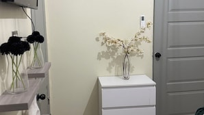 A bathroom with a white vanity, a mirror, and a TV mounted on the wall.