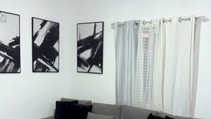 A modern living room with a grey sectional sofa, black cushions, and abstract black and white artwork on the wall.