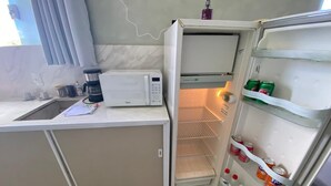 A compact kitchen with a microwave, a coffee maker, and a refrigerator stocked with beverages. - Hotel Araujo's Suítes (Passos)