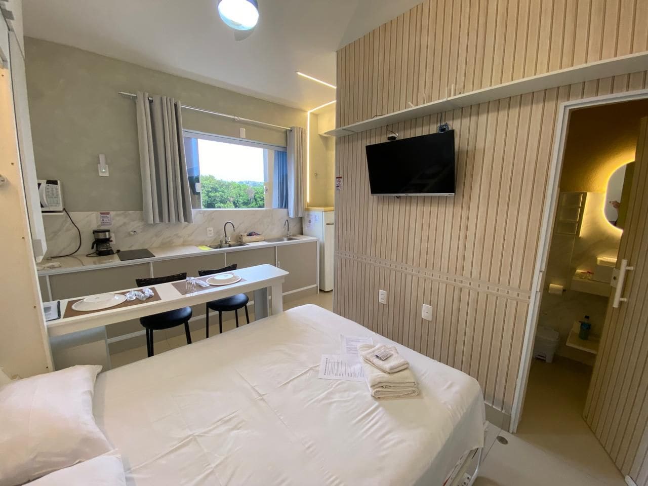Hotellihuone, jossa on sänky, työpöytä, tuoli, televisio ja kylpyhuone.