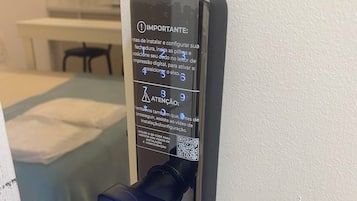 A modern door lock with a QR code and instructions in Portuguese.