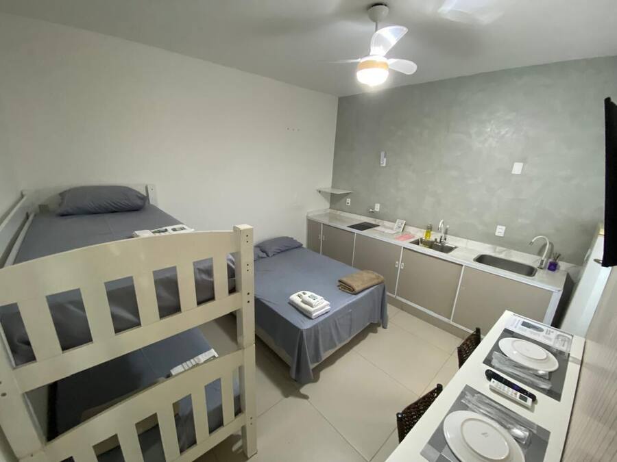 A compact room with a bunk bed, a small kitchenette, and a single bed.