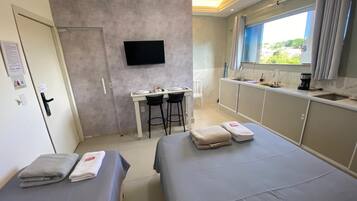A hotel room with a bed, a desk, a TV, and a window with curtains.