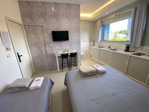 A hotel room with a bed, a desk, a TV, and a window with curtains. - Hotel Araujo's Suítes (Passos)