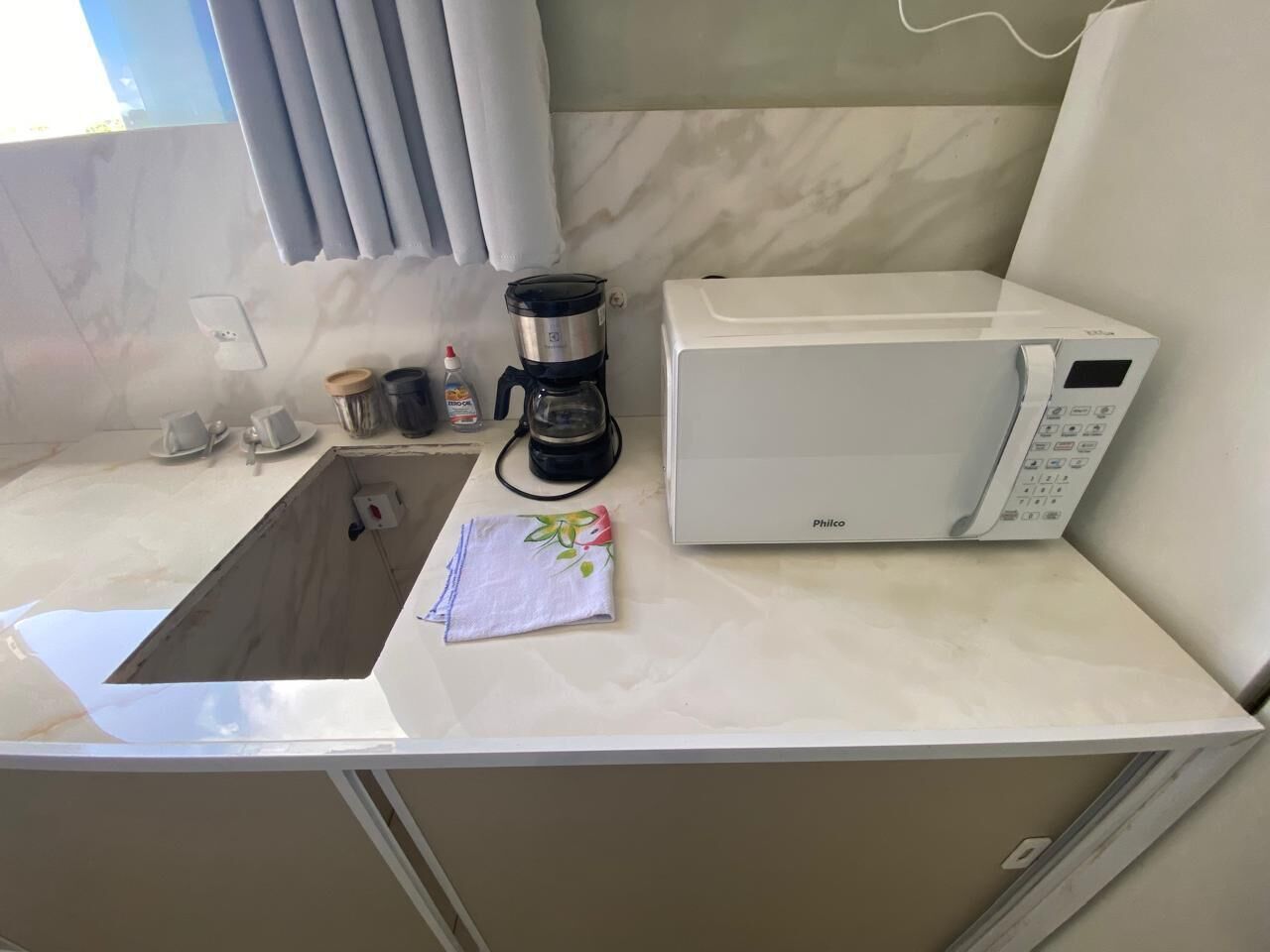 Ett litet kök med diskho, kaffebryggare och mikrovågsugn.