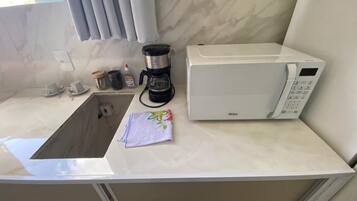 Ett litet kök med diskho, kaffebryggare och mikrovågsugn.