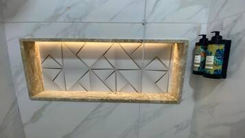 A bathroom with a marble wall, a geometric light fixture, and two bottles of shampoo.