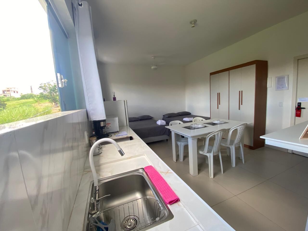 A compact kitchen with a sink, a dining area with chairs, and a sofa.