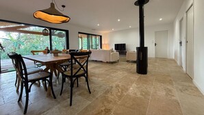 Un salón espacioso con una mesa de comedor, sillas, un sofá y una chimenea negra.