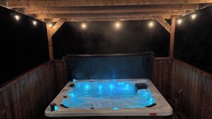 A hot tub under a wooden pergola at night. - The Rustic Roost (Brigus Junction)