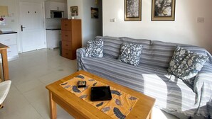 Una sala de estar con un sofá, una mesa de centro de madera e iluminación en el techo.