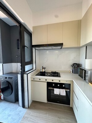 A compact kitchen with a built-in washer, a stove, and an oven. - Perfect 1-bedroom apartment in cool Nairobi with fitness room (Nairobi)