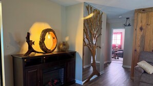 Un salon avec une cheminée, une sculpture en bois et un arbre décoratif.