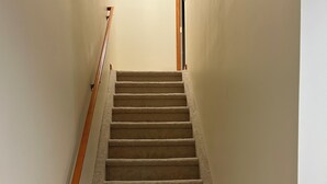 A carpeted staircase with wooden handrails, leading to a door at the top. - Perfect 3-bedroom condo in beautiful Lake Placid for your getaway (Lake Placid)