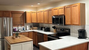 A modern kitchen with wooden cabinets, stainless steel appliances, and a central island. - Perfect 3-bedroom condo in beautiful Lake Placid for your getaway (Lake Placid)