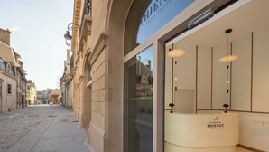 A boutique hotel with a classic European facade, a glass entrance, and a reception desk with a champagne sign. - Le N°3 par Champagne Thiénot (Reims)